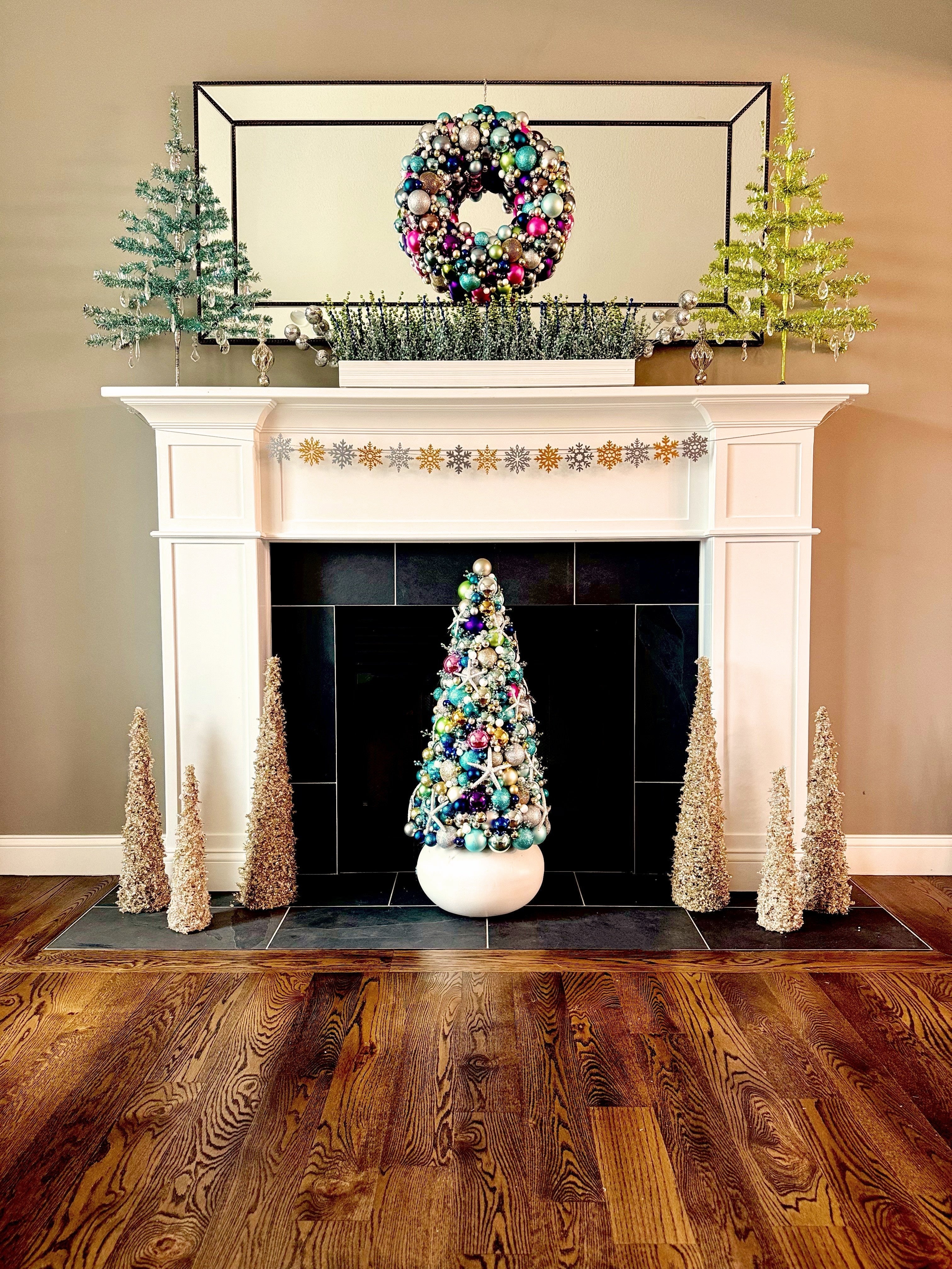 a fireplace mantel decorated with winter greenery featuring a snap banner with gold and silver snowflakes